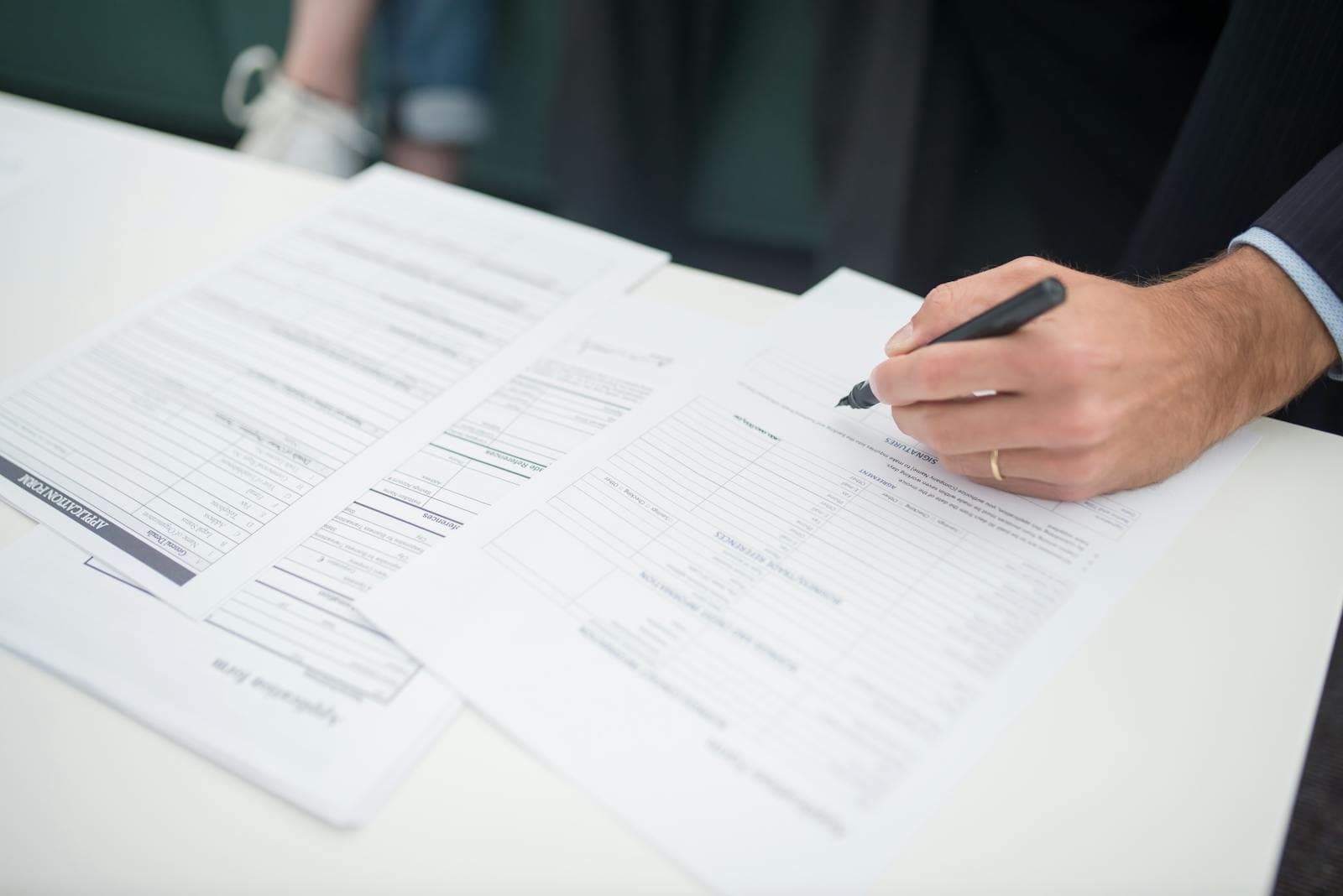 Hand filling out application paperwork on a desk